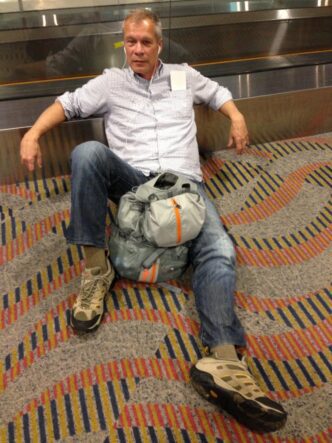 man sitting on airport floor with backpack