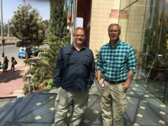 two men standing near glass entrance outdoors
