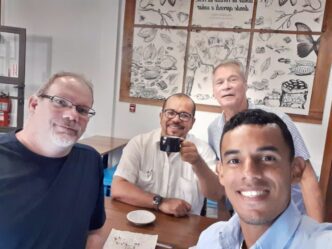Four men smiling at cafe table selfie